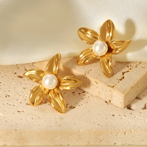Detailed shot of 18k gold flower earrings with pearls on elegant stone and silk
