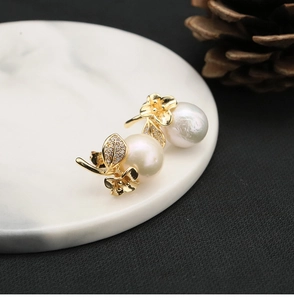 Detailed view of floral pearl earrings with white zircon on a marble tray