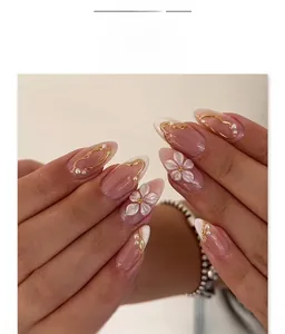 Détail de fleurs 3D gaufrées sur faux ongles avec perles et lignes dorées en forme d'amande