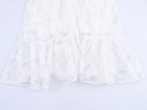 Detailed macro view of white floral lace embroidery and ruffled hemline on the dress
