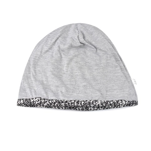 Detail of gray knitted beanie with black and white tweed textured brim and soft fabric