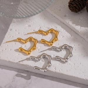 Detailed view of polished heart-shaped earrings in gold and silver finish on stone base