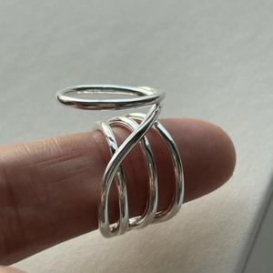 Detail of layered S925 sterling silver cross ring on finger with minimalist hollow design