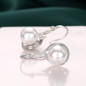 Detailed close-up of silver pearl drop earrings with sparkling zircon crystals