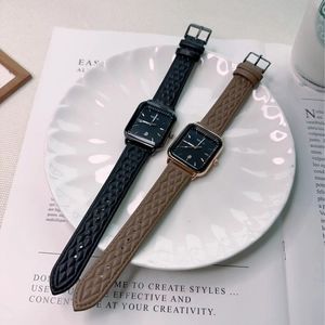 Flat lay of square quartz watches with lattice straps in black and brown finishes