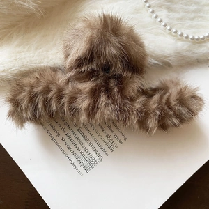 Detailed view of a brown plush hair claw clip placed on an open book with pearls