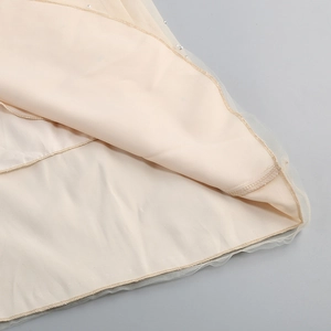 Dettaglio dell'orlo in tulle beige con perline delicate e tessuto a rete a strati