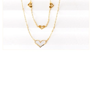 Detail einer zweilagigen Goldkette mit Herz aus weißem Muschelmaterial und Anhängern
