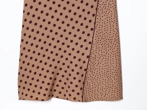 Close-up of brown midi dress featuring patchwork polka dot patterns and woven texture