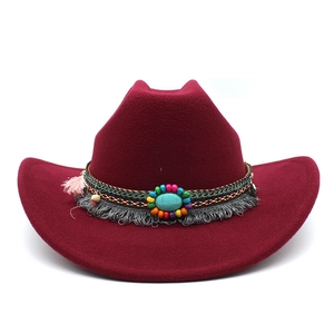 Détail d'un chapeau de cowboy bordeaux avec pierre turquoise et bandeau à pompons ethniques