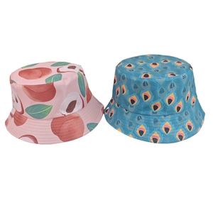 Detail view of reversible bucket hats with peach and peacock feather print patterns
