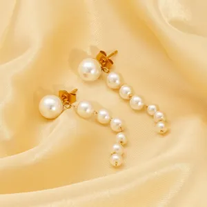 Elegant tiered white pearl drop earrings with golden accents on satin background