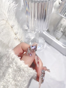 Detail view of 3D crystal hearts and bow decorations on long trapezoid press-on nails
