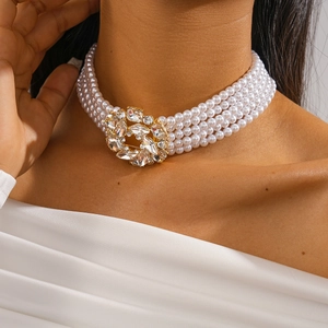 Detail of multi-layer faux pearl choker with crystal-encrusted gold flower clasp