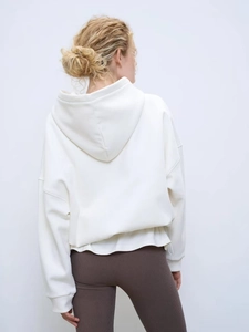 Vue arrière d'un sweat à capuche blanc oversize pour femme avec legging côtelé marron