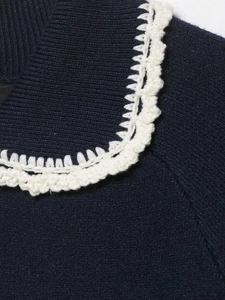 Detail of navy knit cardigan collar with white crochet scalloped edges in macro view