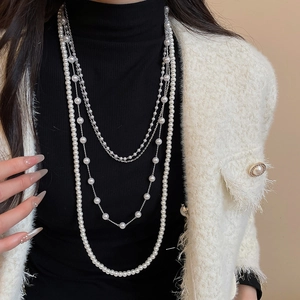 Elegant multi-layer pearl necklace shown on a model with a black turtleneck and tweed jacket