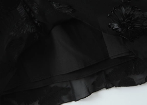 Detailed close-up of 3D floral embroidery on a black mesh fishtail dress hem