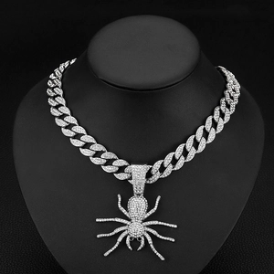 Macro detail of silver hip hop Cuban chain necklace featuring an iced-out spider pendant