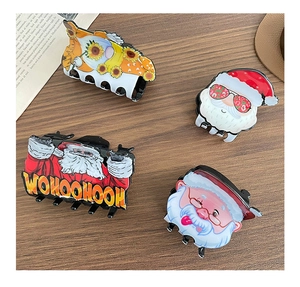 Detailed view of four festive Christmas Santa Claus acrylic hair claws on a wood surface