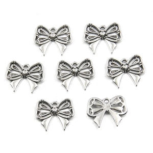 Close-up of seven silver hollow bow pendants for DIY jewelry making and necklaces
