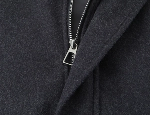 Close-up of metallic silver zipper and premium wool texture on a navy bomber jacket