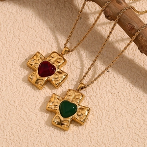 18K gold plated heart and cross pendant necklace with twisted rope chain on textured background