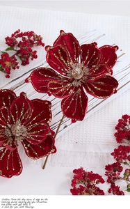 Detail of red velvet Christmas magnolia flowers with golden sequins on white wooden background