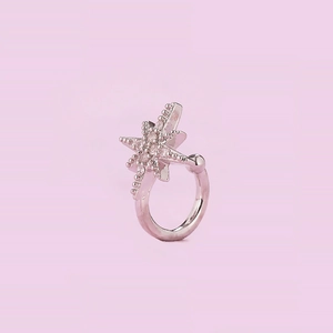 Macro detail of silver star ear cuff featuring pavé cubic zirconia on soft purple background