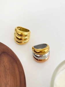 Detailed view of chunky triple-layered polished gold and tri-color stacked dome rings