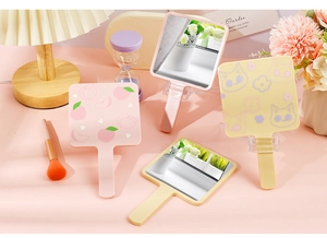 Detailed view of portable peach and cat pattern hand mirrors on a pink vanity desk