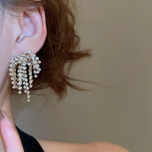Close-up of elegant gold tassel earrings with waterfall rhinestones on a female model