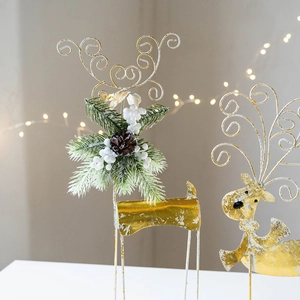 Golden metal reindeer Christmas ornament with pine needles and berries on desk