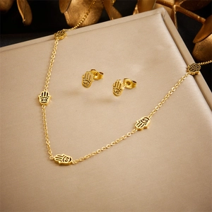 Golden Hamsa hand jewelry set with necklace and stud earrings on an elegant display