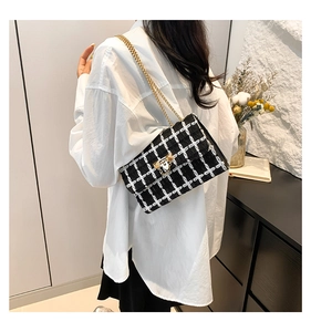 Model wearing a black and white tweed plaid shoulder bag with a gold chain strap
