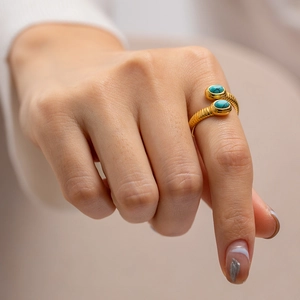 Detail of 18K gold-plated snake wrap ring with blue lapis lazuli on model's finger