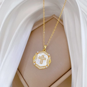 Gold titanium necklace with cross pendant and pearls in a jewelry box over white silk