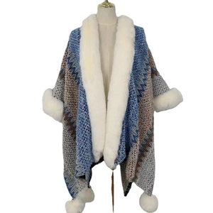 Ethnic knit shawl cloak with white faux fur collar and pom-poms in geometric pattern