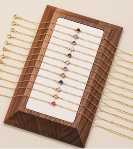 Detail of gold chain bracelets with various colored zircon stones on a display stand