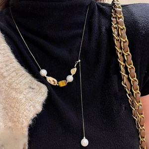 Y-Halskette im Vintage-Stil mit Tigerauge und Perlen auf einem schwarzen Pullover