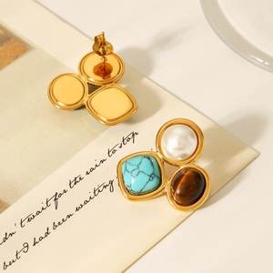 Detail of vintage gold earrings with inlaid white pearl, turquoise, and brown tiger eye stone