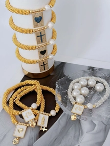 Detail of bohemian pearl bracelet set with religious charms and gold textured beads