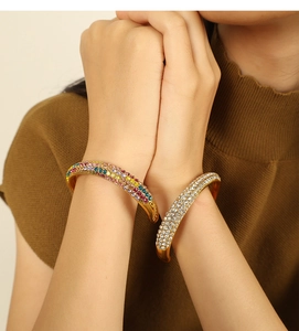 Detail of elegant gold bracelet featuring three rows of pavé zircons and white beads