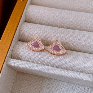 Detail of rose gold fan shaped earrings with purple stone and pave diamonds