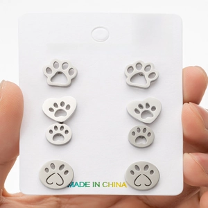 Close-up of four pairs of stainless steel paw print stud earrings on a display card