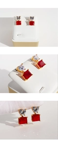 Detail view of red square gemstone earrings with heart-shaped zircon and gold plating