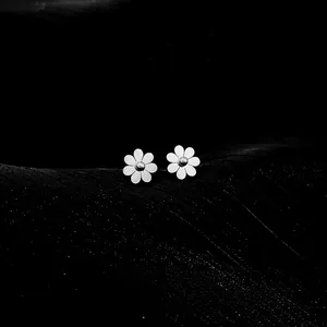 Macro shot of minimalist daisy stud earrings with white petals and steel center ball