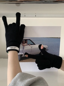 Detail of black knitted touchscreen gloves featuring a white denim classic fabric label