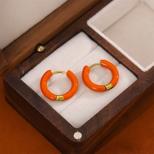 Orange enamel gold hoop earrings displayed in a walnut wood jewelry box with white lining