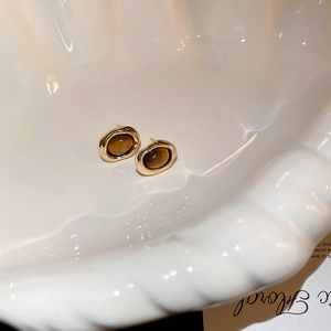 Detailed close-up of vintage oval amber-tone stud earrings on elegant shell texture